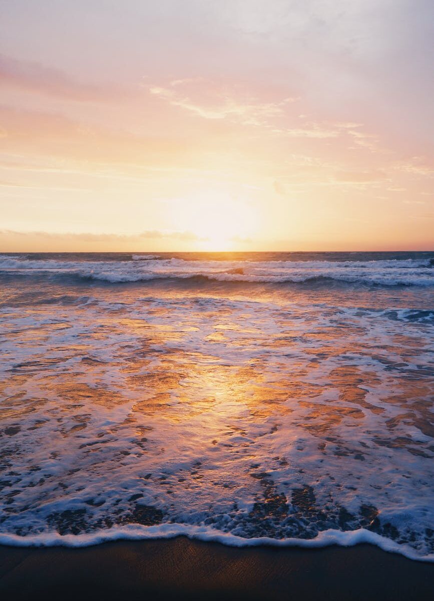 photo of ocean waves near seashore during sunset